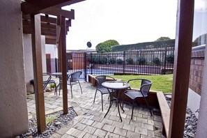 An outdoor patio with a pergola, a round table, and four chairs. - Cascades Lakefront Motel (Taupo)
