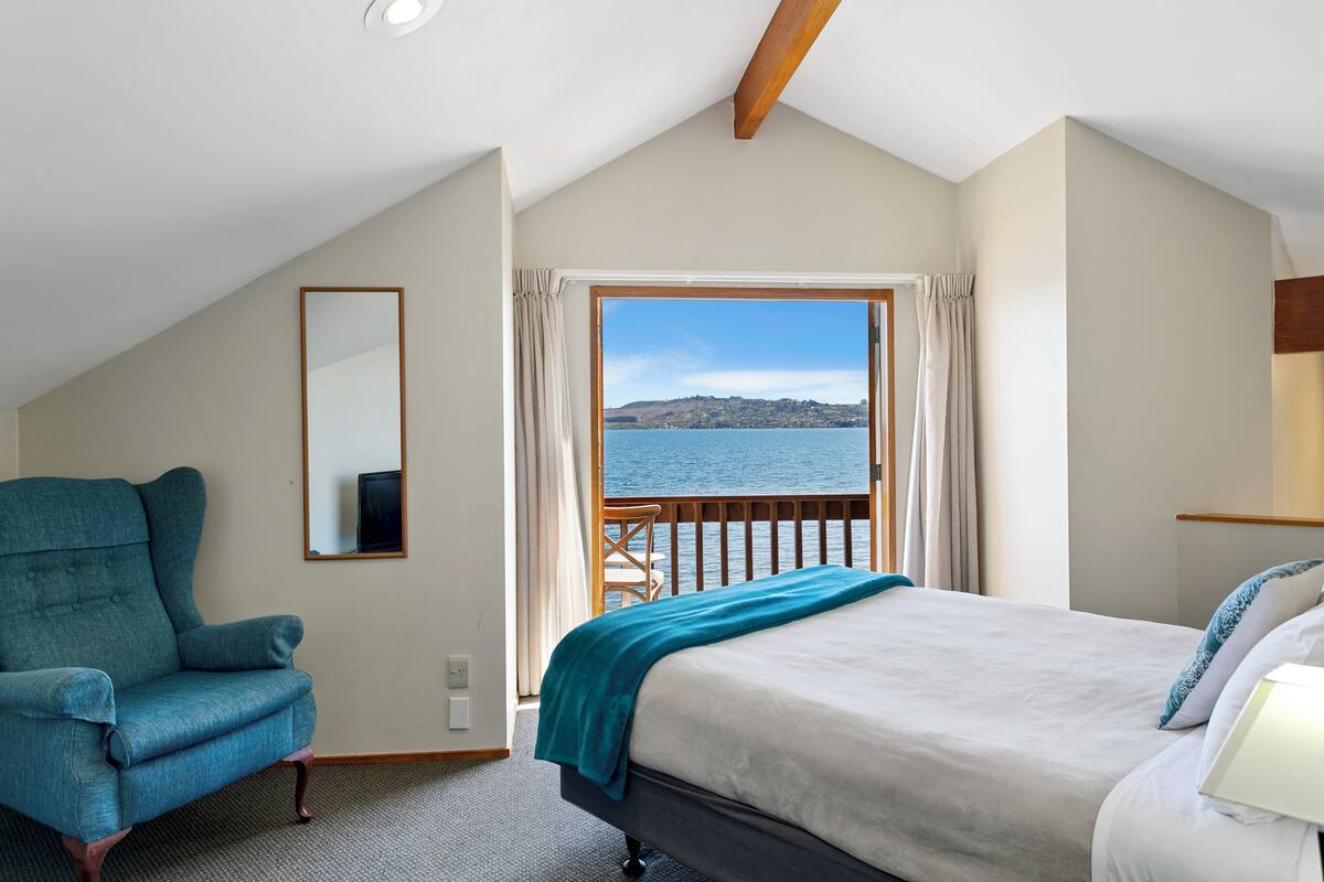 Une chambre avec un lit, une chaise, une fenêtre avec des rideaux et une vue sur la mer.