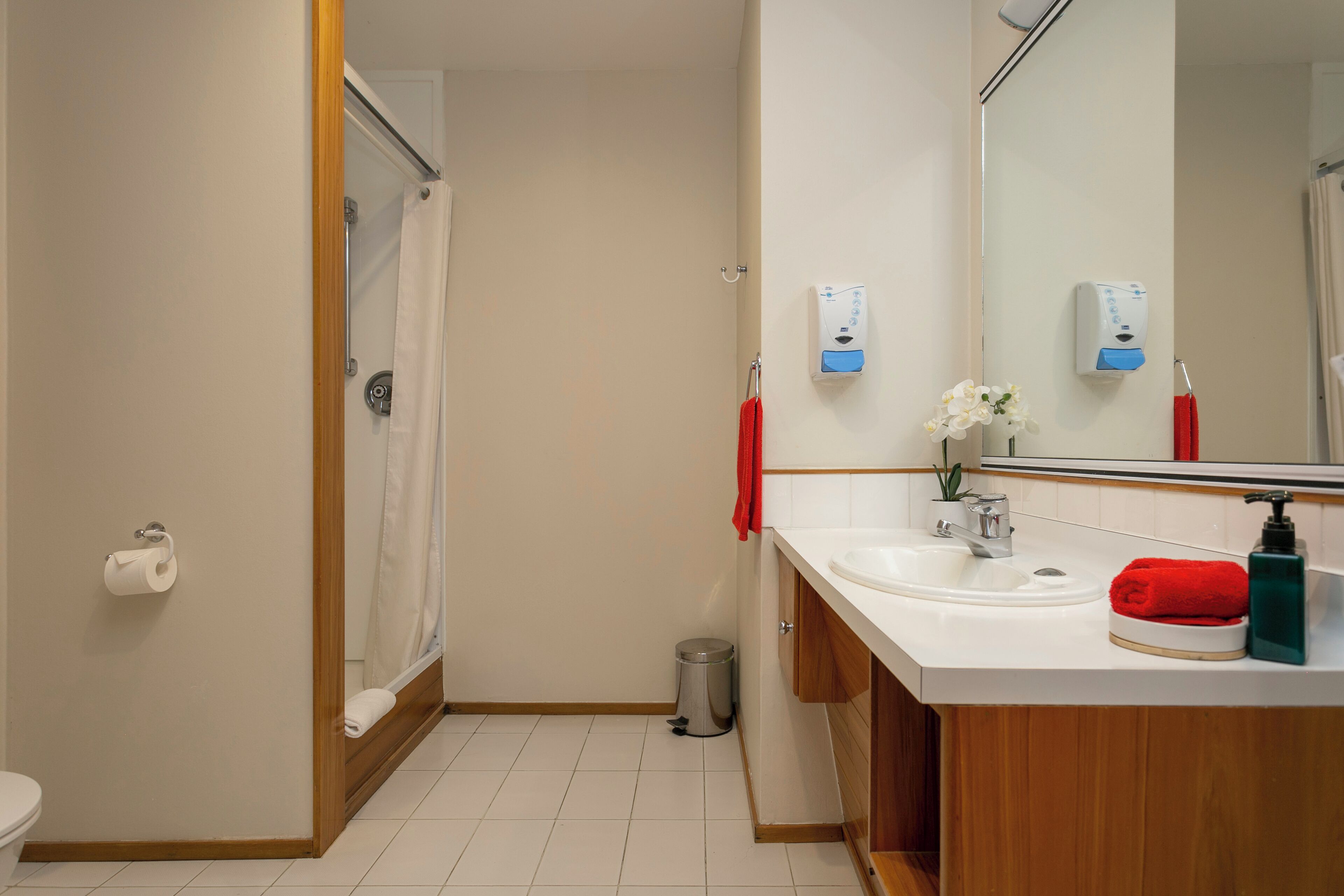 Un baño moderno con ducha, inodoro, lavamanos y secador de manos.