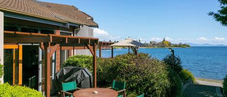 A patio with a table and chairs, a covered grill, and a view of the lake.