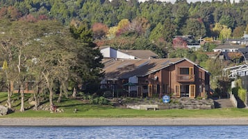 Situated on a grassy area, this single-family home offers a view of a body of water and a forested hill.