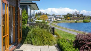 A modern building with large windows and a view of a lake and surrounding houses. - Cascades Lakefront Motel (Taupo)