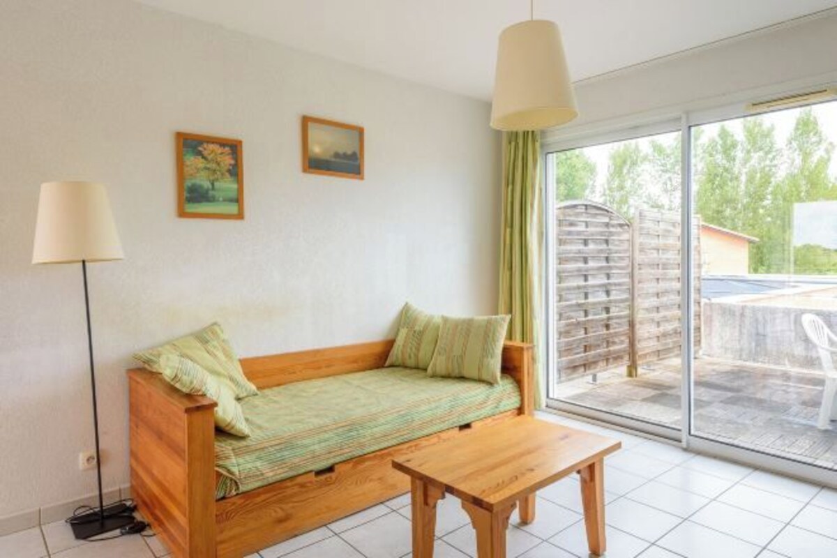 Een kamer met een houten bank, een kleine tafel en een schuifdeur naar een buitenruimte.