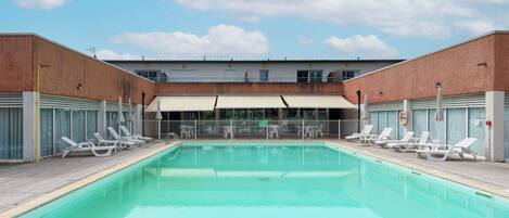 Una piscina al aire libre de temporada, sombrillas