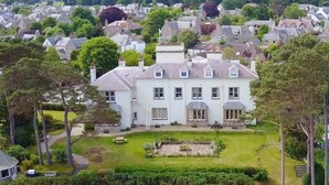 A large, white, two-story house with a well-maintained garden and a stone pathway leading to the entrance. - Invernairne Guest House (Nairn)