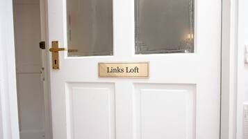 A white door with a brass handle and a nameplate that reads "Links Loft".