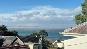 Une vue côtière avec des maisons, une mer et une chaîne de montagnes à l’horizon.
