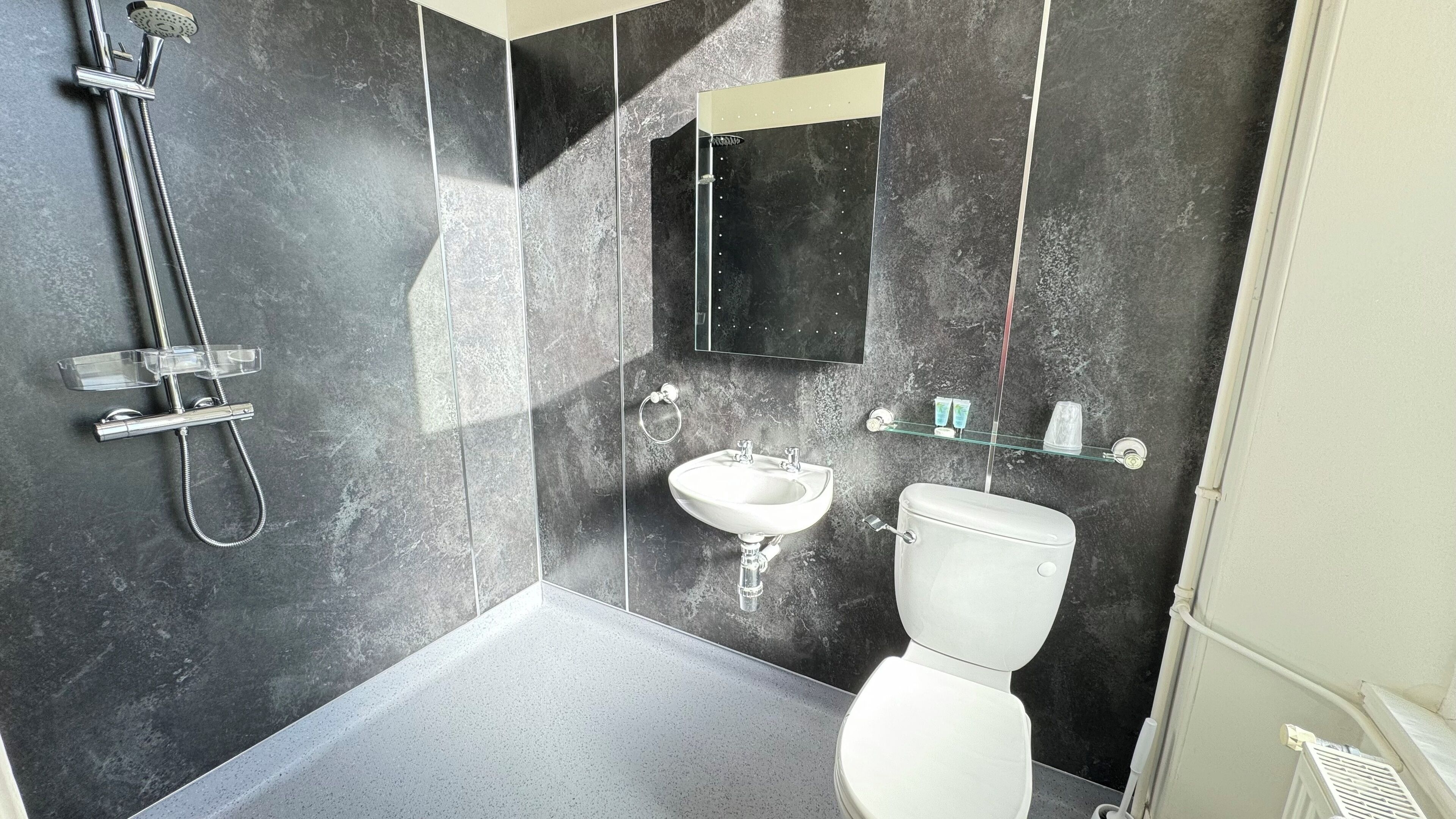 Un baño moderno con ducha, lavamanos, inodoro y espejo.