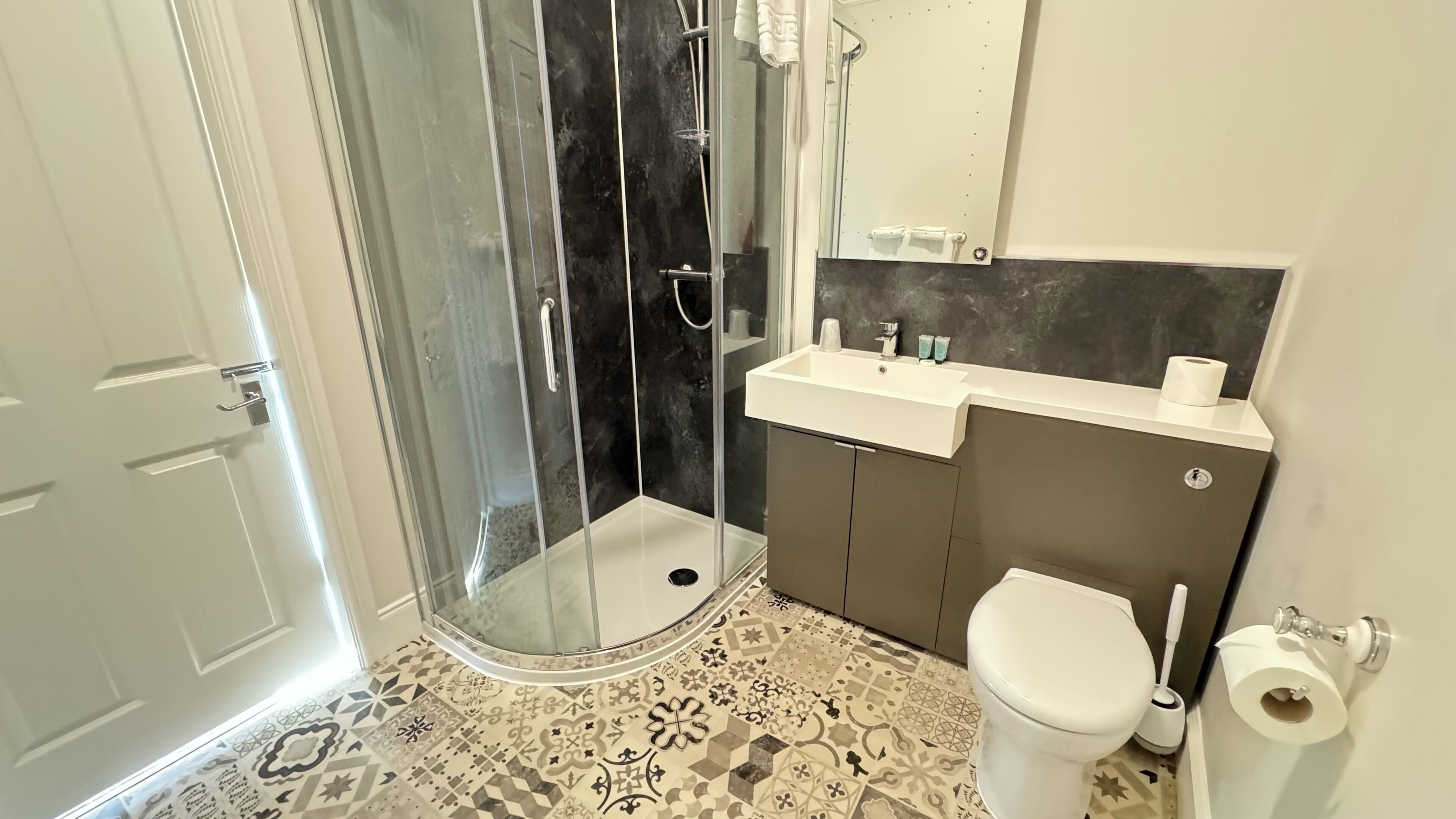 Ein Badezimmer mit Dusche, Toilette, Waschbecken und Spiegel.