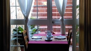 Mesa para dos con vista a un muro de ladrillo y plantas afuera.