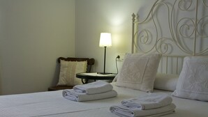 Una cama bien hecha con toallas dobladas, una lámpara de noche y un cabecero decorativo.