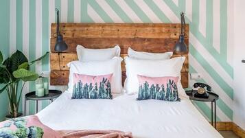 Una cama con ropa de cama blanca, dos almohadas decorativas, un cabecero de madera y dos lámparas de noche.
