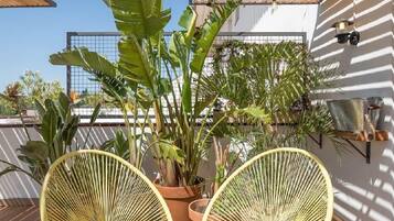 Een terras met twee gele stoelen, een kleine tafel en een plant in een pot.