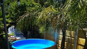 A circular pool with a blue cover, surrounded by a white picket fence, and various potted plants. - a'Vue Guesthouse (Cape Town)