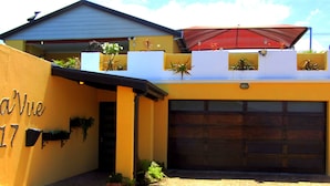 A building with a yellow facade, a garage door, and outdoor plants. - a'Vue Guesthouse (Cape Town)