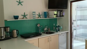 A kitchen with a green backsplash, a coffee maker, a kettle, a microwave, and a sink. - a'Vue Guesthouse (Cape Town)