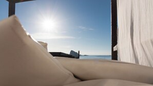 A sunlit beach view from a room with a bed and a view of the ocean. - Hotel Oasi (Lipari)