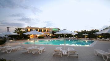 Alberca al aire libre, sombrillas en la alberca y camastros