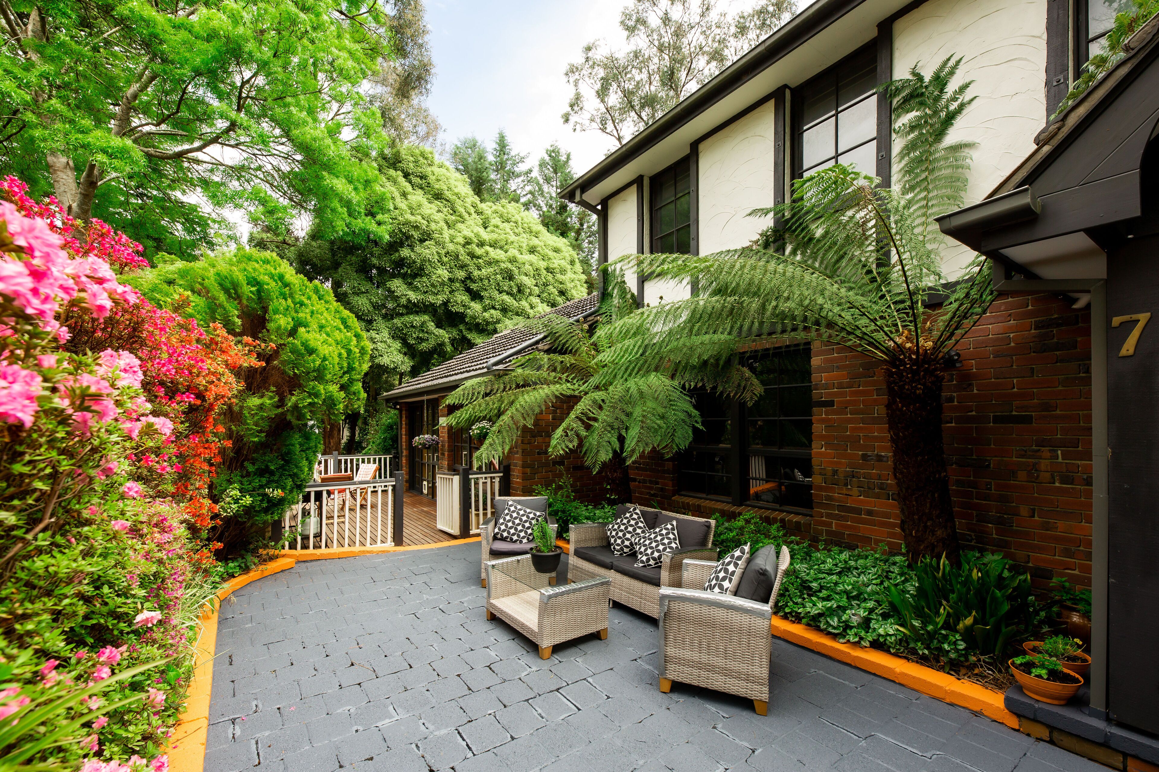 A courtyard with outdoor seating, lush greenery, and a building with a brick facade.