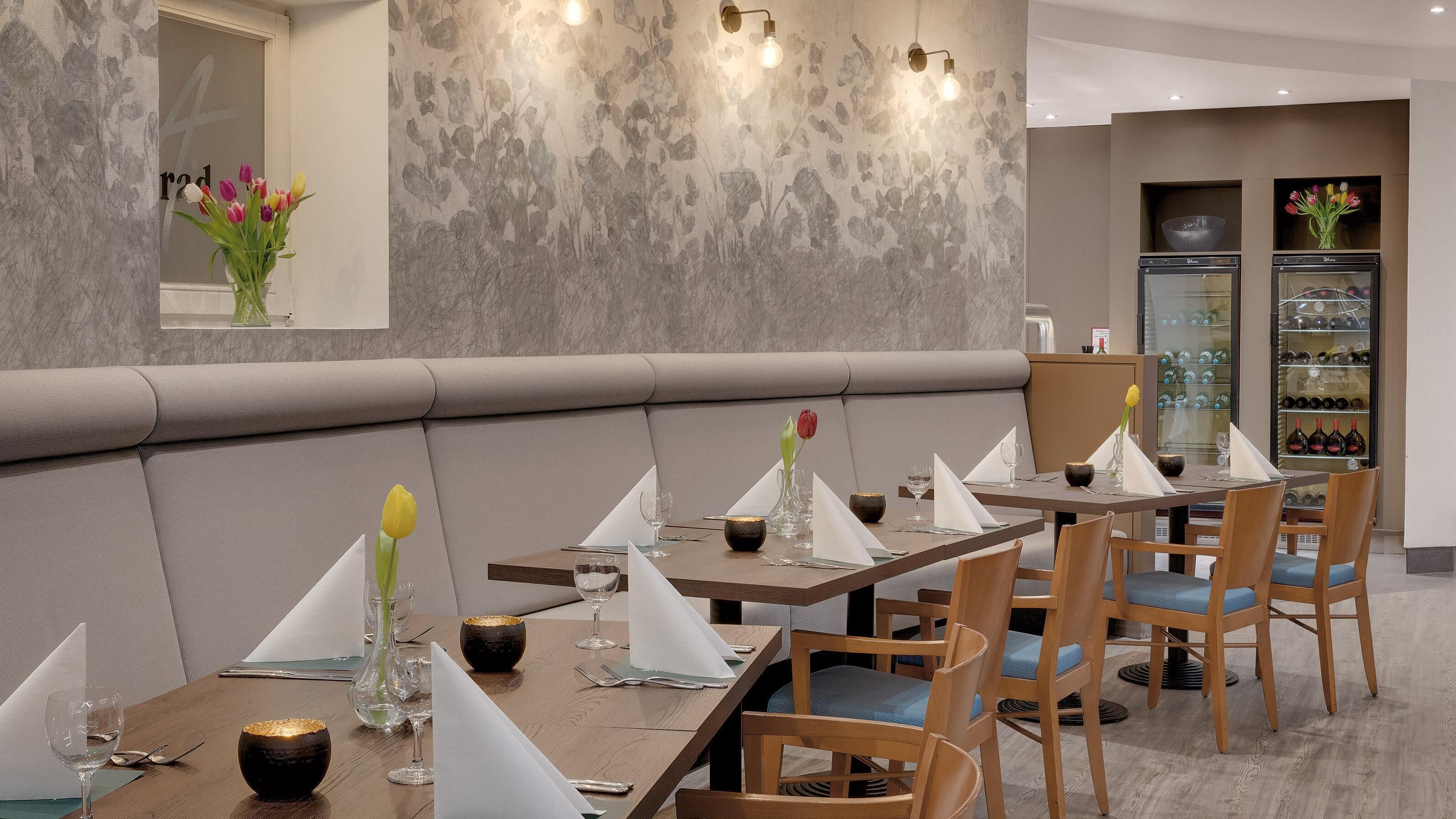 Un restaurante con una decoración moderna, con mesas y sillas de madera, y una exhibición de vinos.