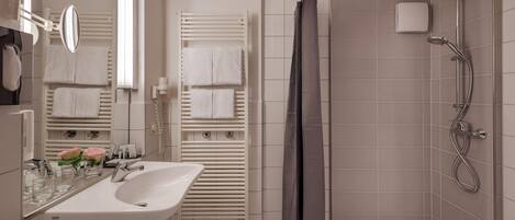 Un baño moderno con lavamanos, espejo y toalleros blancos.