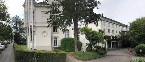 A large, white building with a classic architectural style, featuring a prominent entrance and a well-maintained garden area.