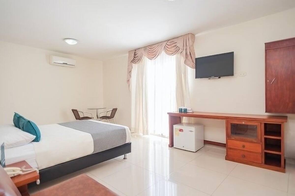 A hotel room with a bed, a desk, a television, and a wardrobe.