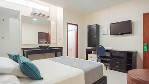 A hotel room with a bed, a desk, a chair, a television, and a wardrobe.