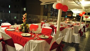 A banquet hall with tables set for a formal event, featuring white and red tablecloths and chairs.