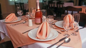 A table set for a meal with a bottle of wine, glasses, and neatly folded napkins.