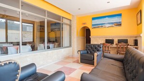 A hotel lobby with a checkered floor, leather sofas, a dining area, and a painting of a beach scene.
