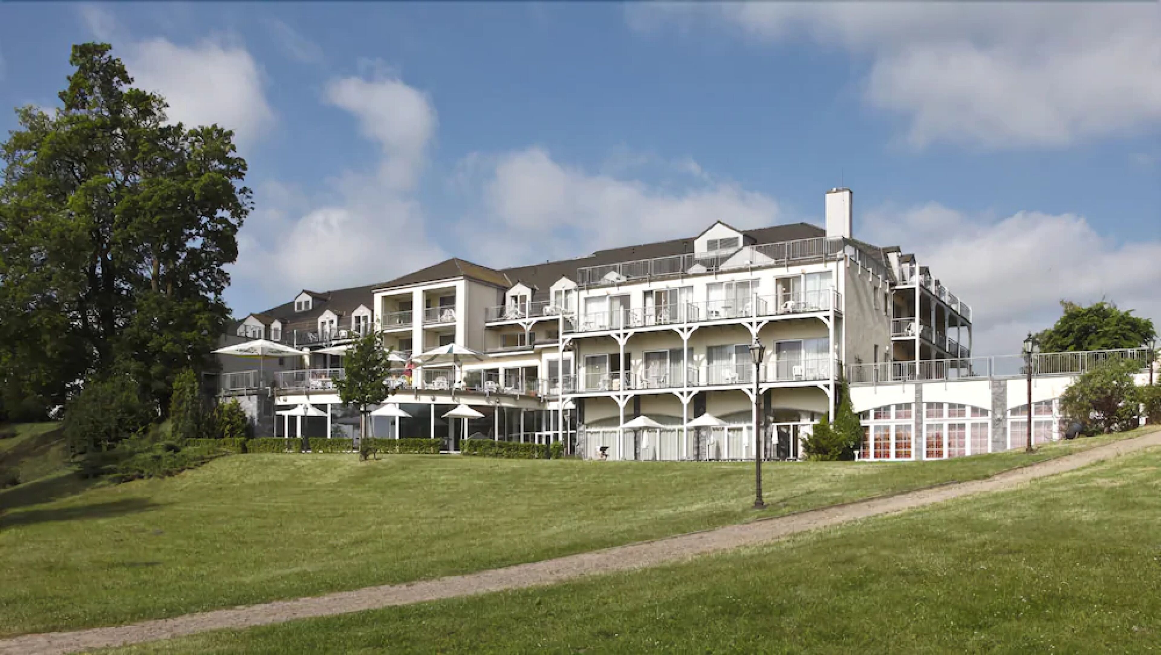 A multi-story hotel with balconies, a lawn in the foreground, and a clear sky.