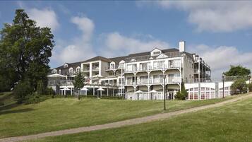 A multi-story hotel with balconies, a lawn in the foreground, and a clear sky.