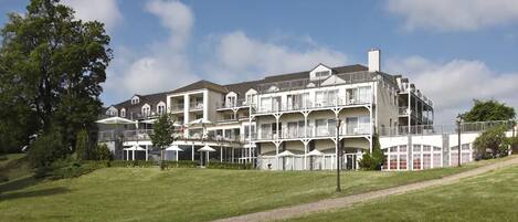 A multi-story hotel with balconies, a lawn in the foreground, and a clear sky.