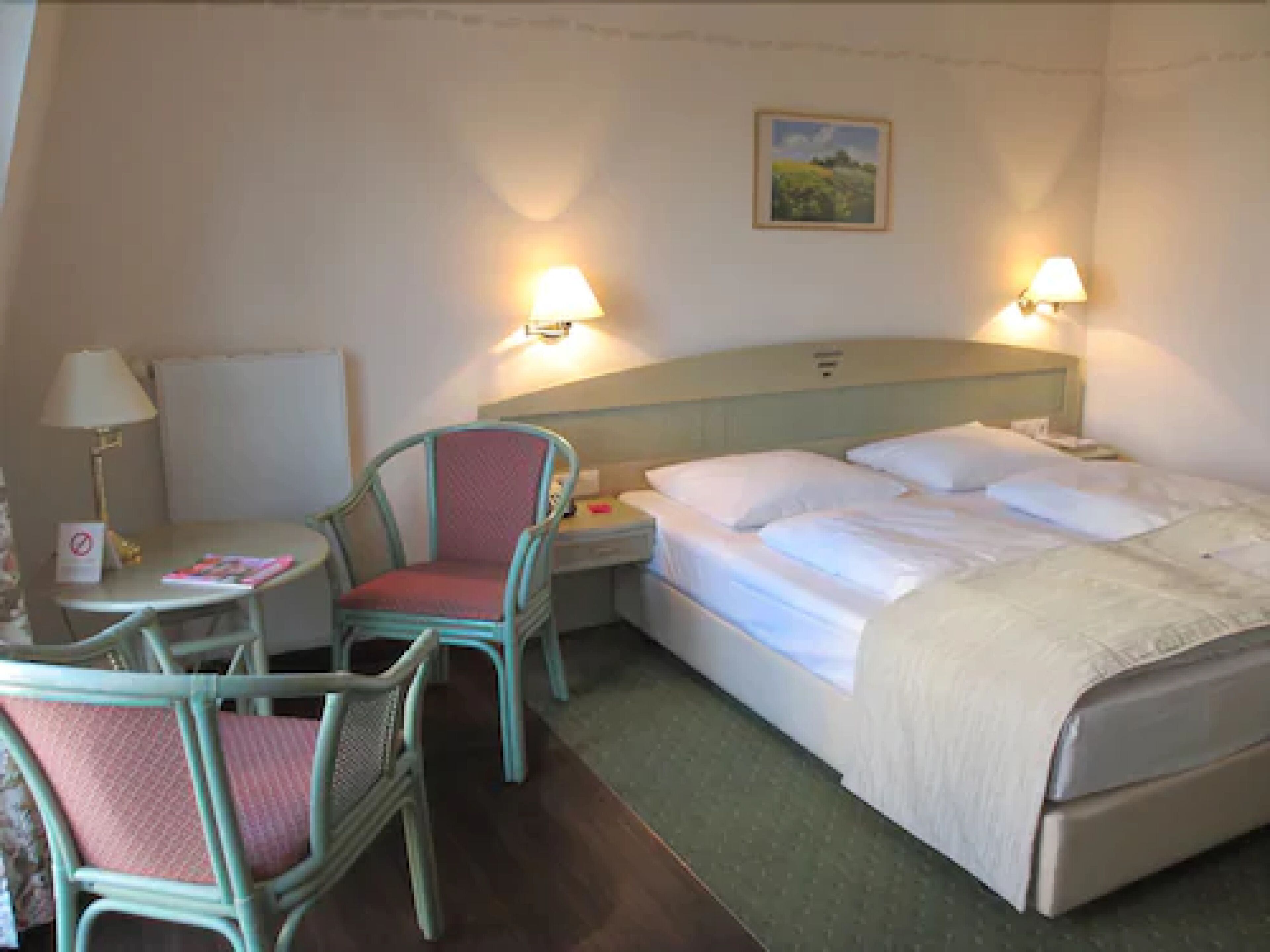 Ein Hotelzimmer mit Bett, Stuhl, Schreibtisch und Nachttisch.