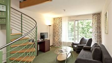 A living room with a green spiral staircase, a sofa, a glass coffee table, and a television.
