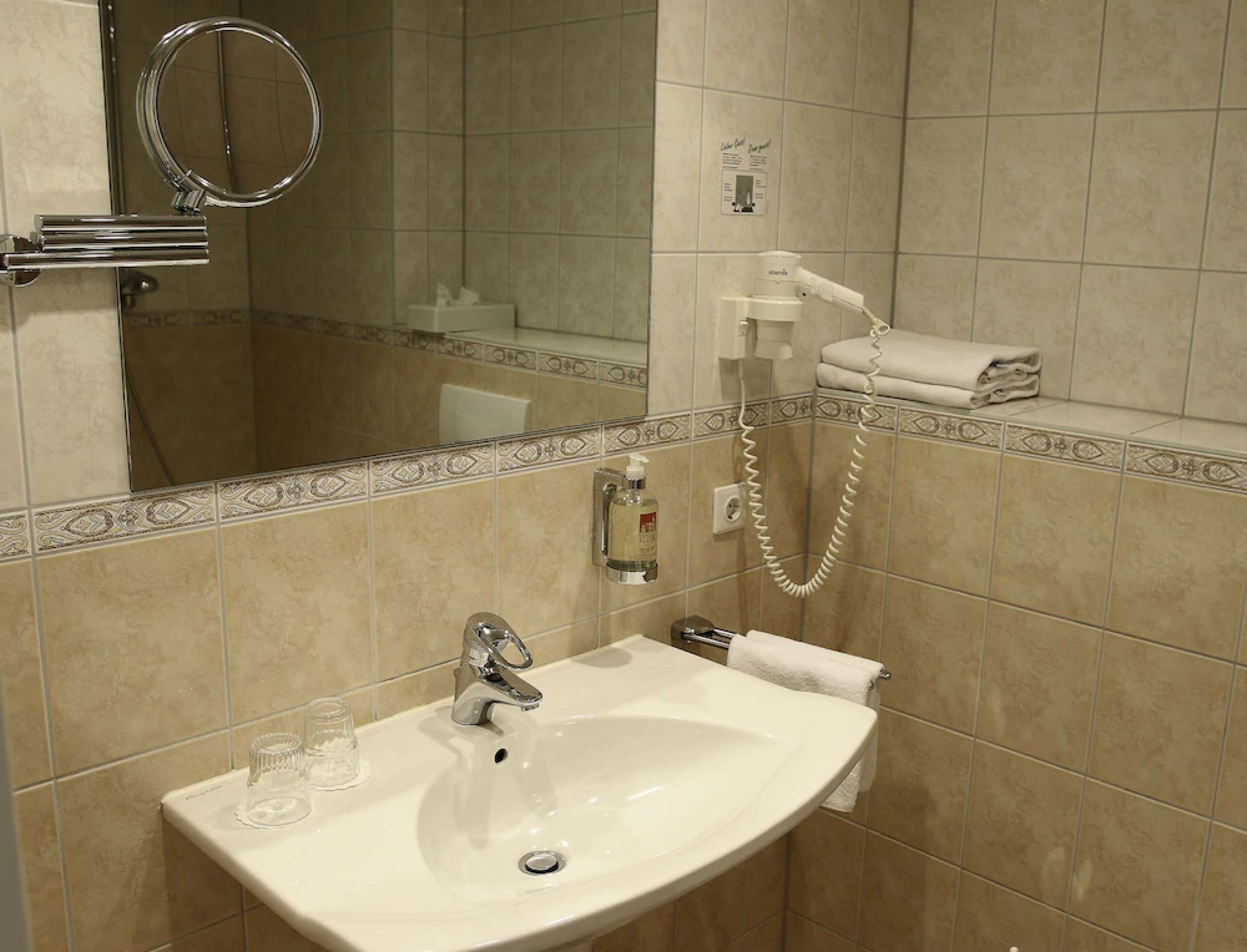 A bathroom with a sink, mirror, towel rack, and a hand dryer.