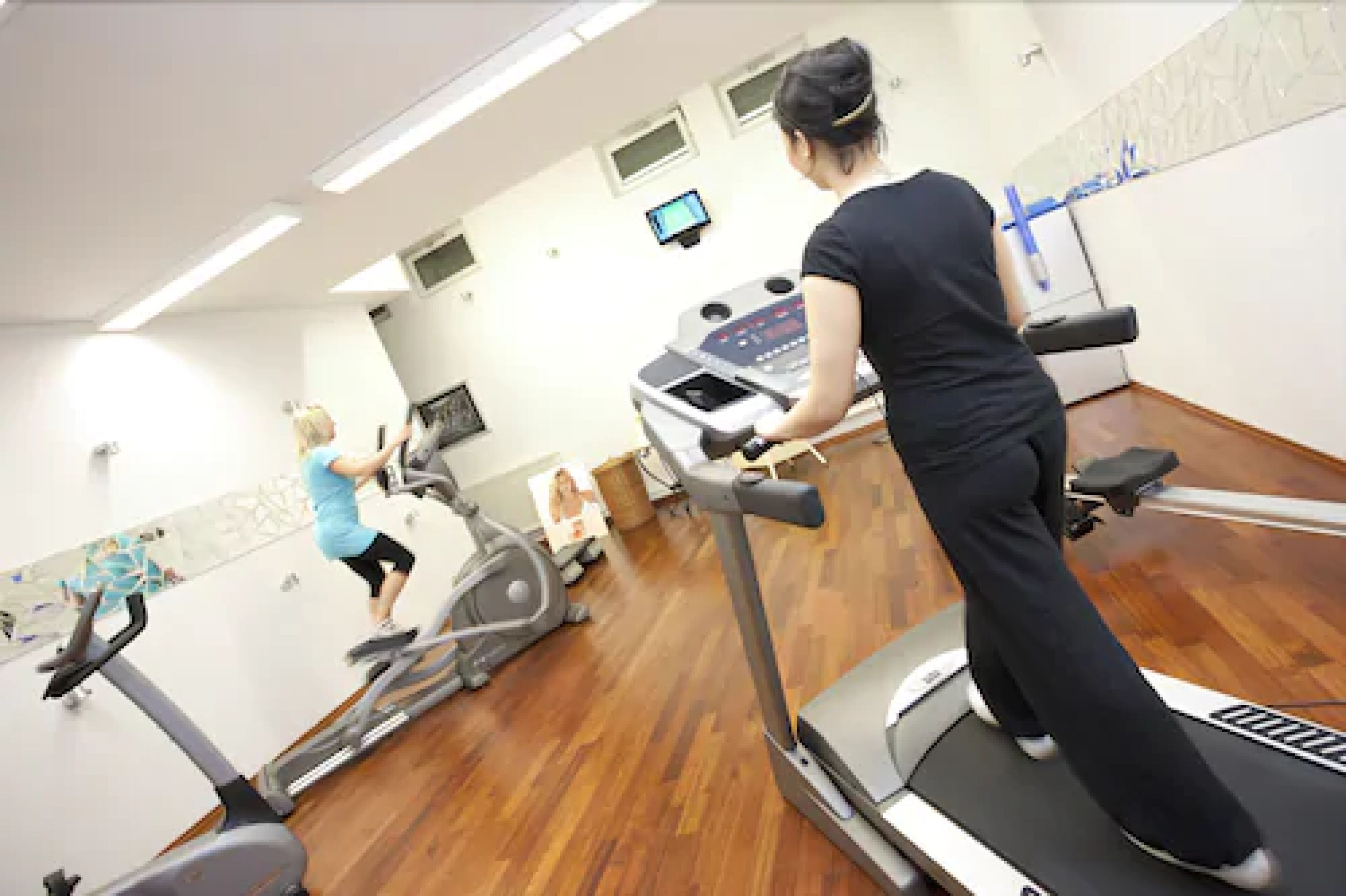 Une salle de sport équipée de tapis de course, de vélos d’appartement et d’un appareil d’aviron.