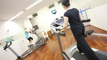 Une salle de sport équipée de tapis de course, de vélos d’appartement et d’un appareil d’aviron.