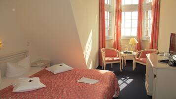 Ein Hotelzimmer mit einem Bett, zwei Stühlen, einem Schreibtisch und einer Lampe.