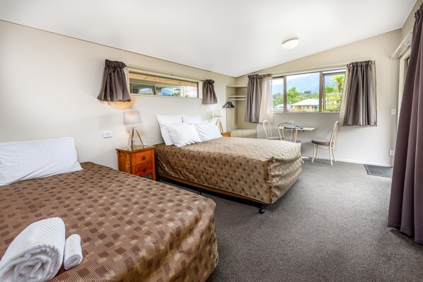 A hotel room with two beds, a desk, and a chair. - 10 Cottages (Franz Josef Glacier)