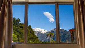 Una ventana con vistas a una cadena montañosa y una palmera.