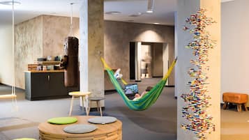 A modern lounge area with a hammock, seating, and a unique wall art installation.