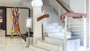 Una escalera moderna con escalones de mármol y barandillas de madera, que conduce a un piso superior.
