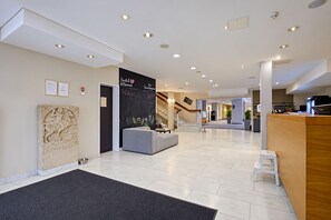 A modern hotel lobby with a reception desk, a staircase, and a blackboard with welcome messages. - Seminaris Sunday Hotel Bad Honnef (Bad Honnef)