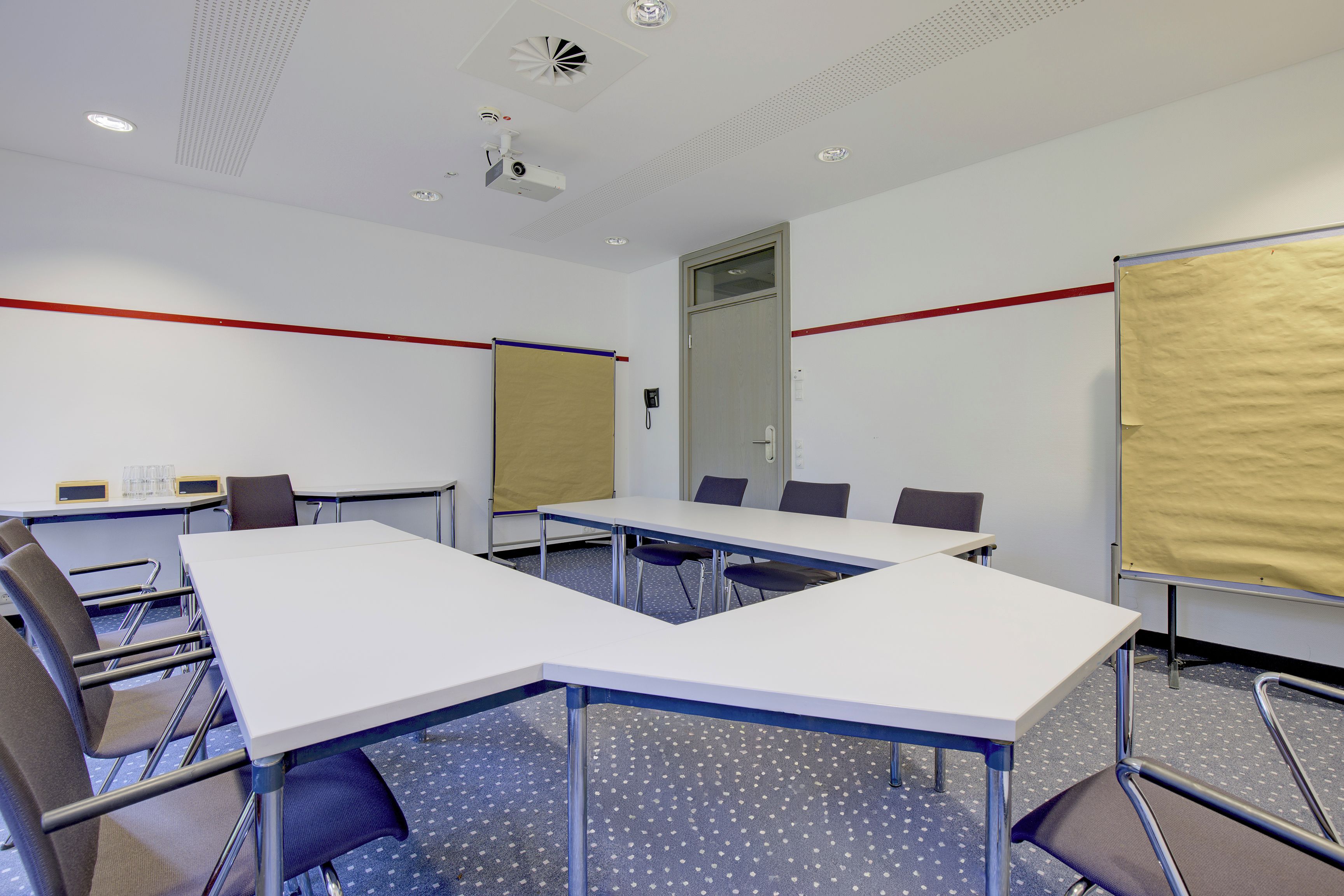 Una sala de conferències amb una taula gran, cadires, un projector i una pissarra.