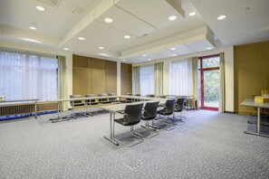 A conference room with a long table, multiple chairs, and a view through a window. - Seminaris Sunday Hotel Bad Honnef (Bad Honnef)