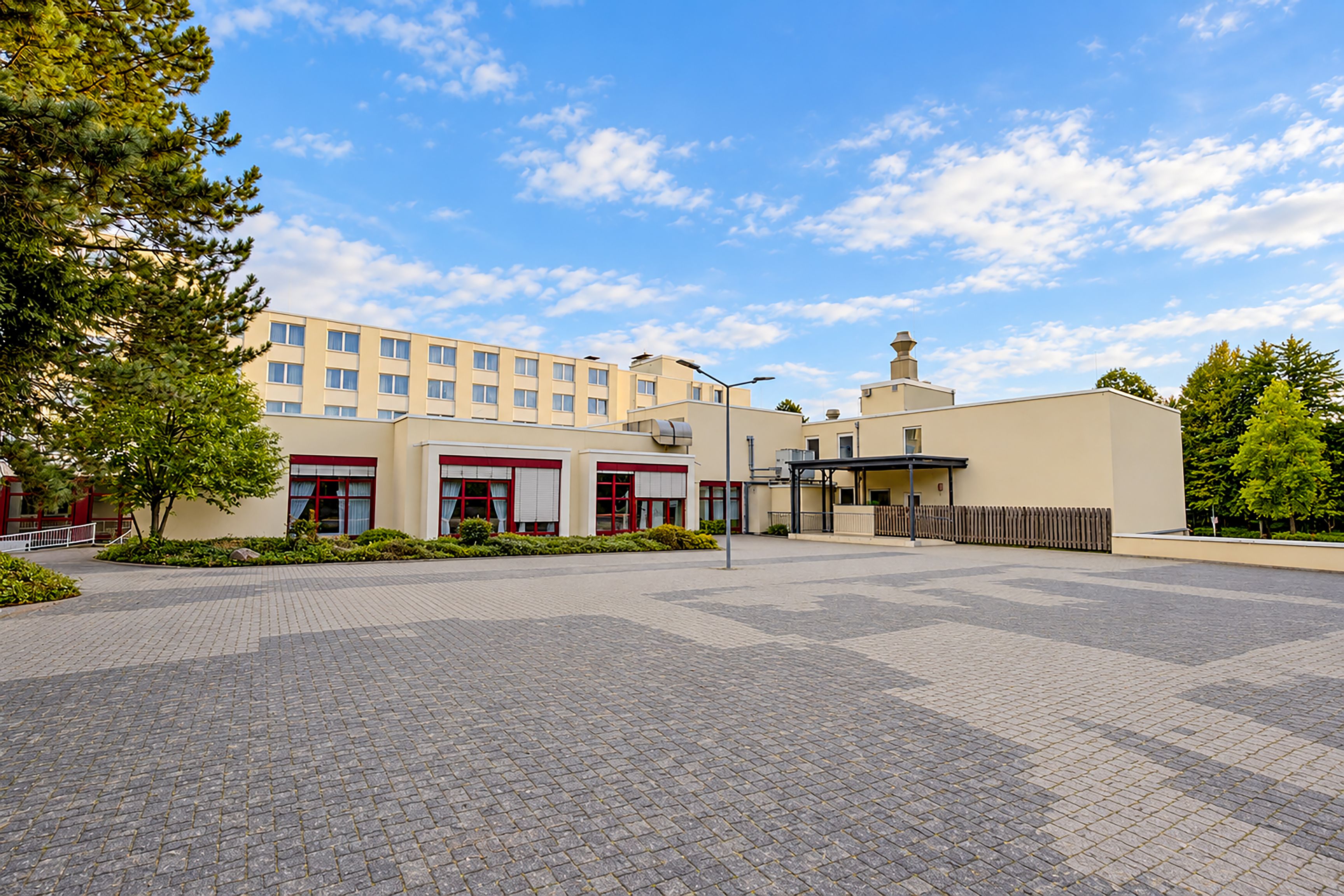 A hotel with a paved courtyard, multiple buildings, and a clear sky.