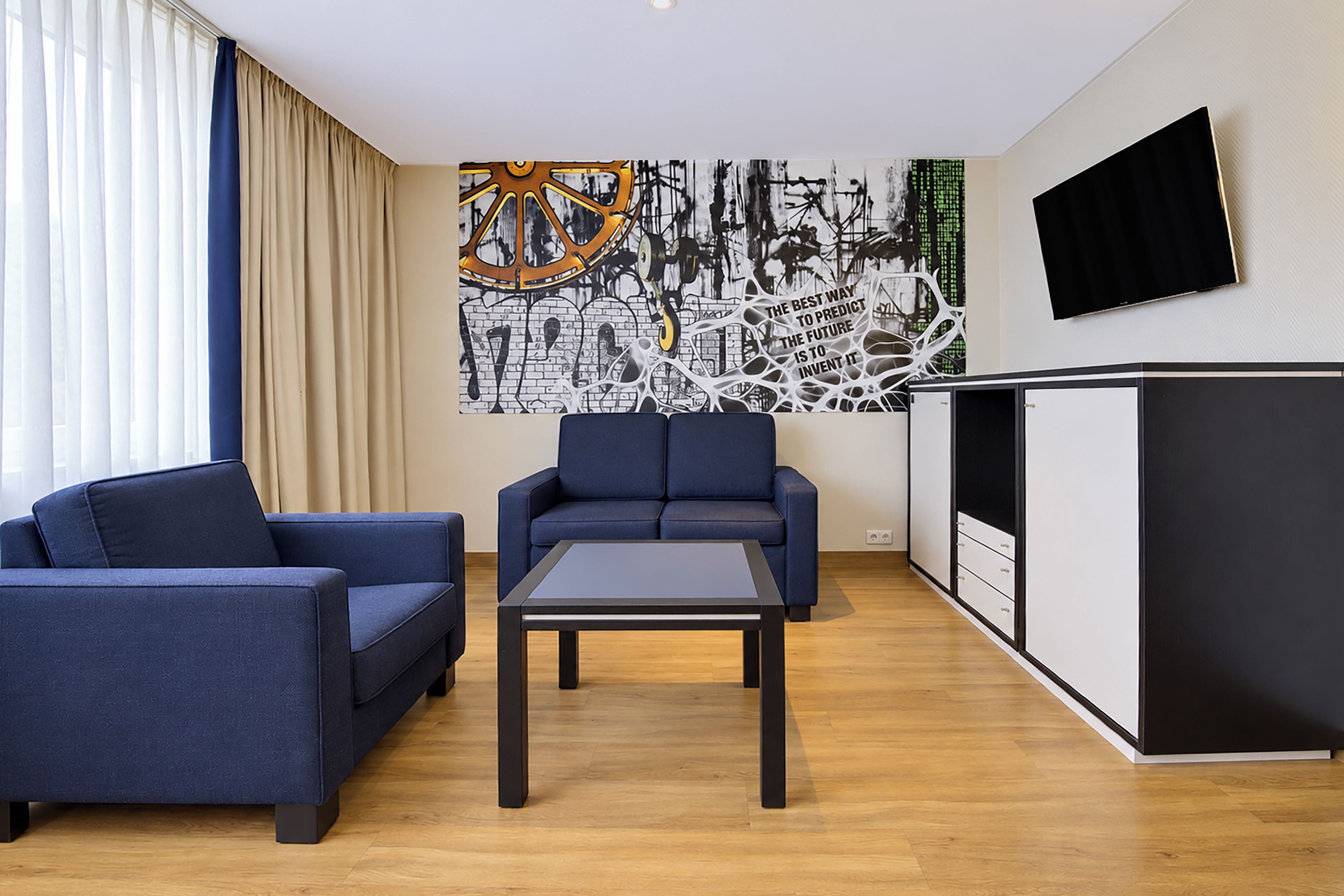 Una sala de estar moderna con un sofá, una mesa de centro y un televisor montado en la pared.