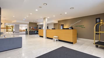 Een modern ingerichte receptie met een receptiebalie, een klein krukje en een gouden trolley.